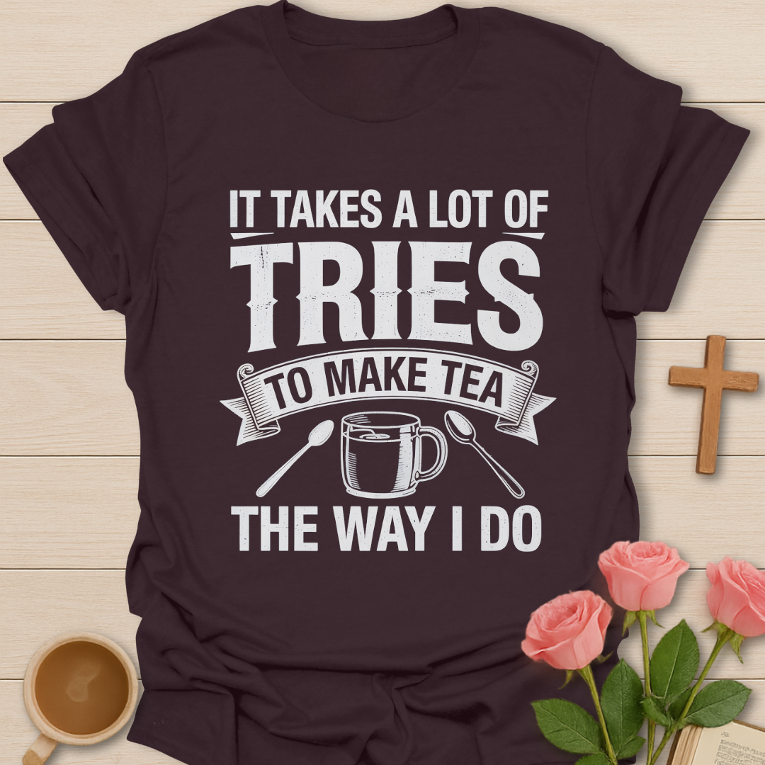 Black t-shirt with humorous tea-making quote on a wooden surface with a cup of tea and roses.