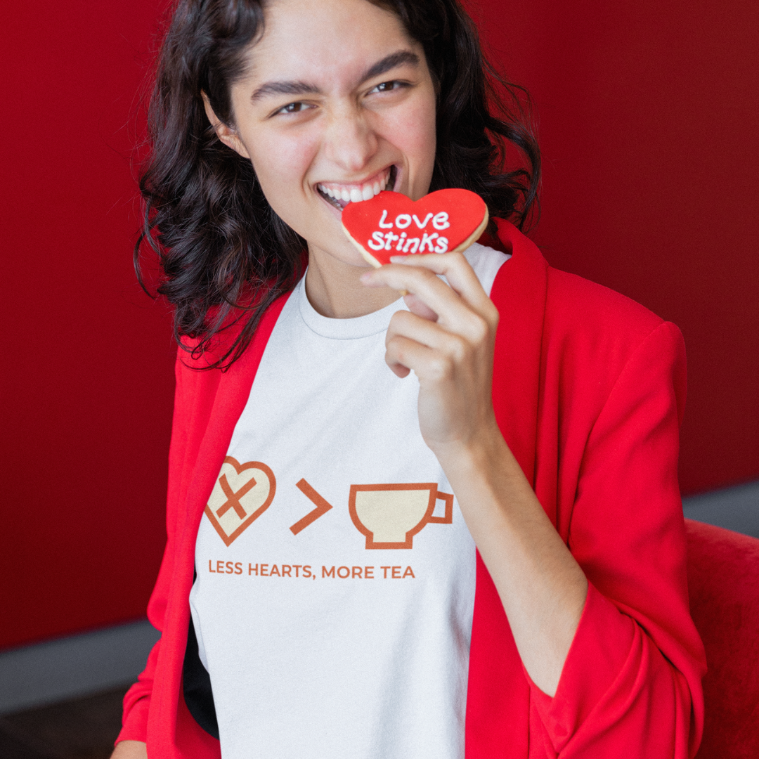 Person wearing a shirt with a humorous design and holding a 'Love Stinks' heart-shaped cookie against a red background.