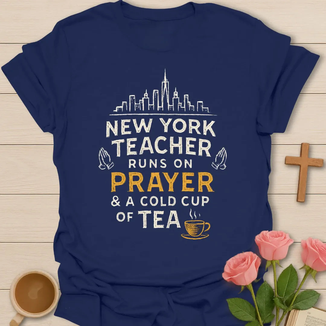 New York Teacher Runs On Prayer shirt with skyline, praying hands, distressed cream lettering, gold prayer text, and small teacup. - Navy