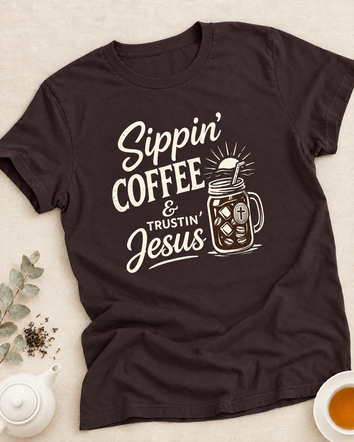 Woman in a The Lord Is My Barista T-shirt holding a coffee cup beside an open Bible and teapot in a soft neutral room, with Coffee & Faith collection text above.