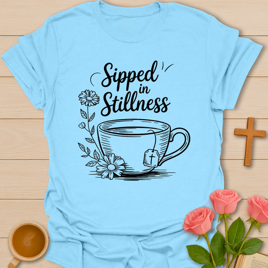 Light Blue Christian t-shirt design featuring a teacup with a cross tea tag, floral elements, and the phrase “Sipped in Stillness” symbolizing faith and quiet reflection