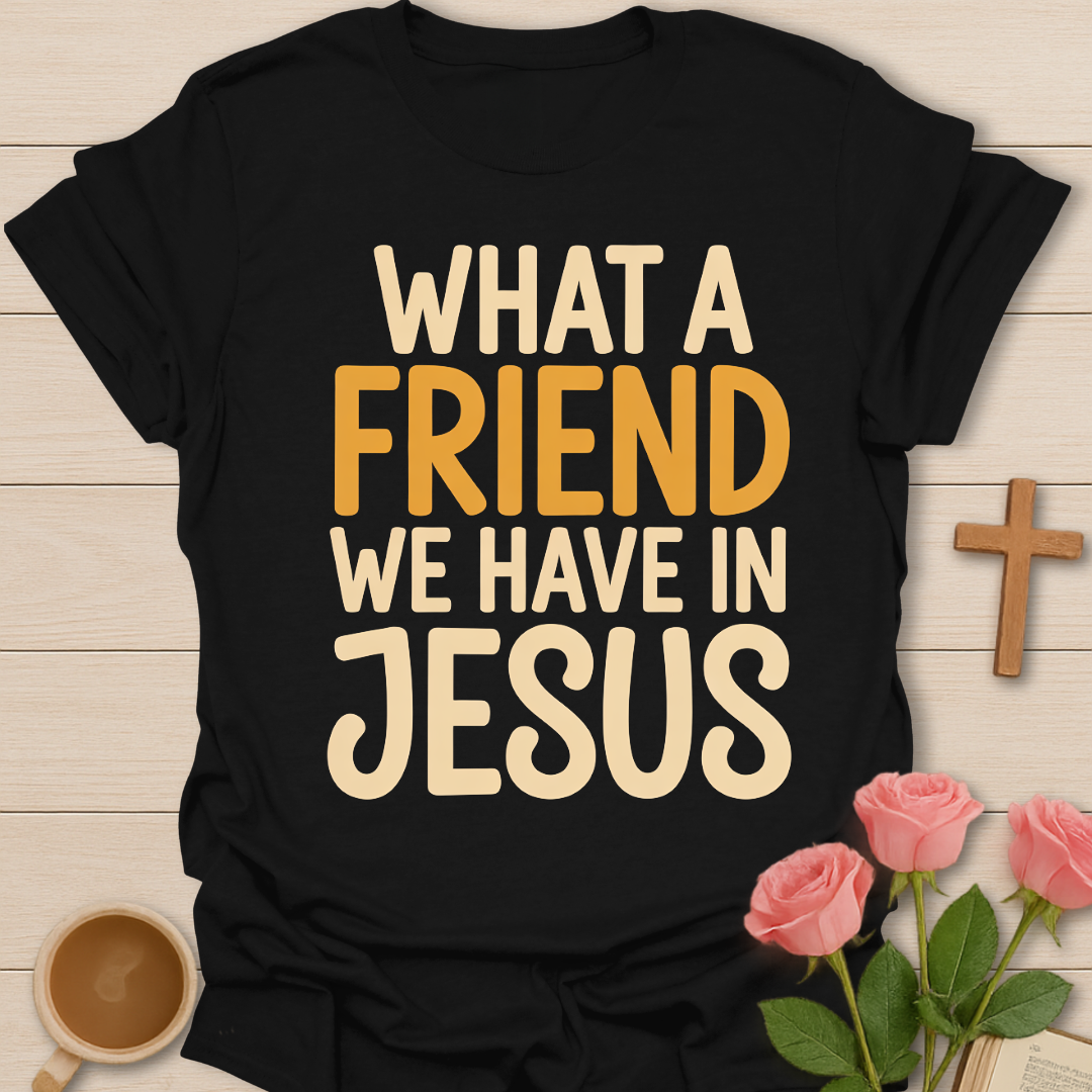 Black t-shirt with 'What a friend we have in Jesus' text on a wooden surface with flowers and a cross.