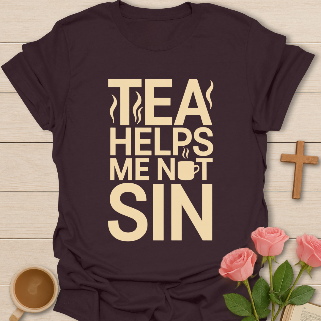 Black t-shirt with 'Tea Helps Me Not Sin' text on a wooden surface with a cup of tea and roses.