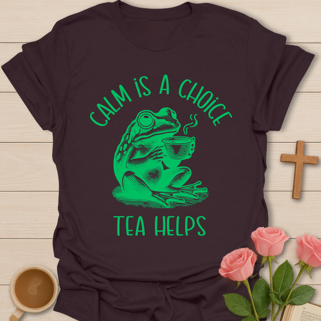 Dark Chocolate t-shirt with green frog graphic and text 'Calm is a choice, tea helps' on a wooden surface with flowers and a cup.