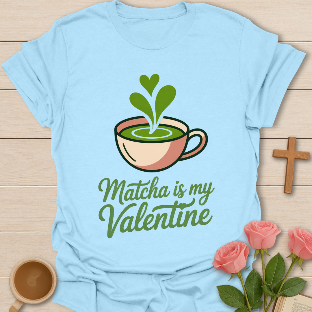 Light blue t-shirt with matcha graphic and text 'Matcha is my Valentine' on a wooden surface with flowers and a cup.