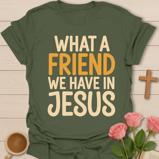 Green t-shirt with 'What a friend we have in Jesus' text on a wooden surface with flowers and a cross.