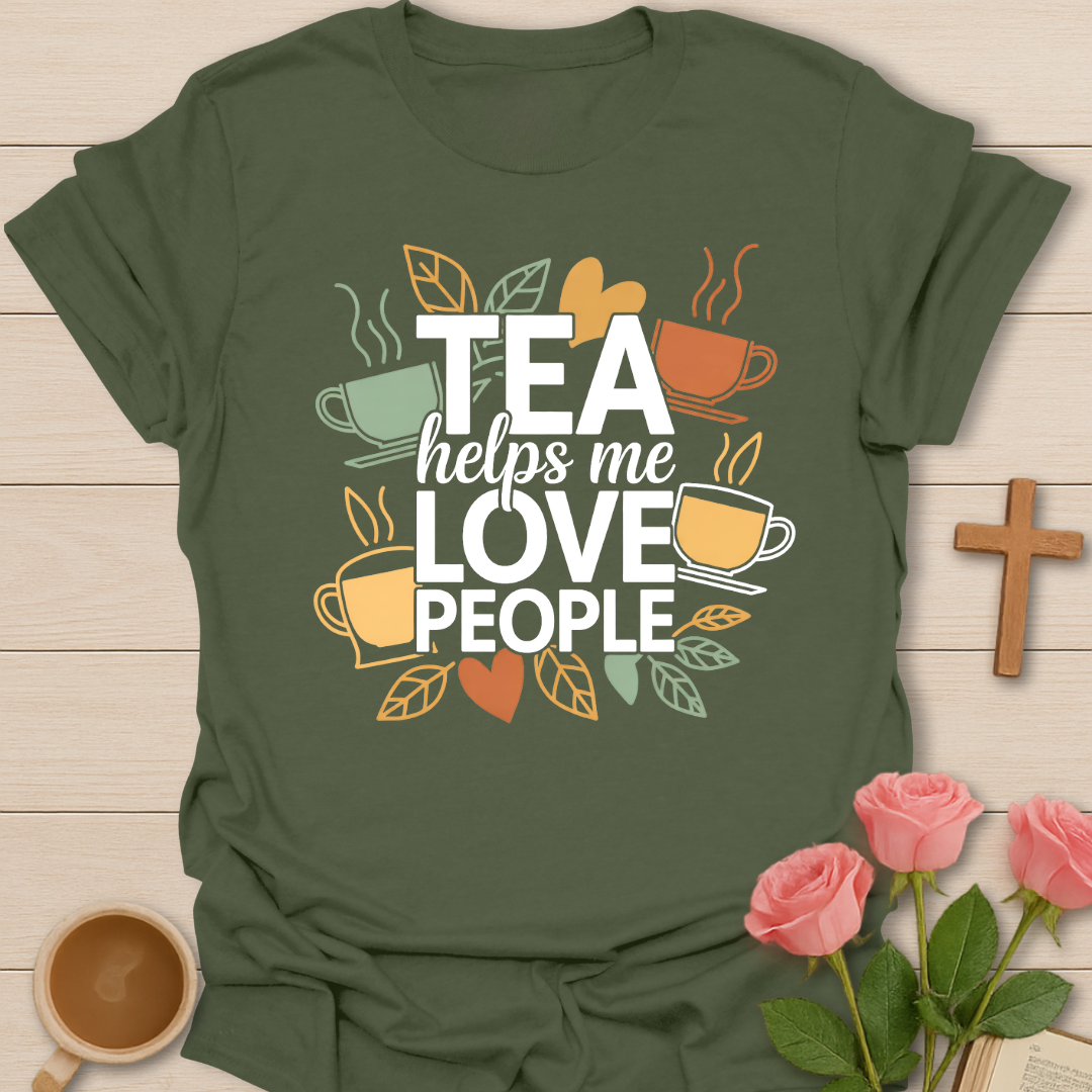Green t-shirt with illustrated tea cups and leaves surrounding the phrase “Tea Helps Me Love People” in warm earthy tones on a dark background.