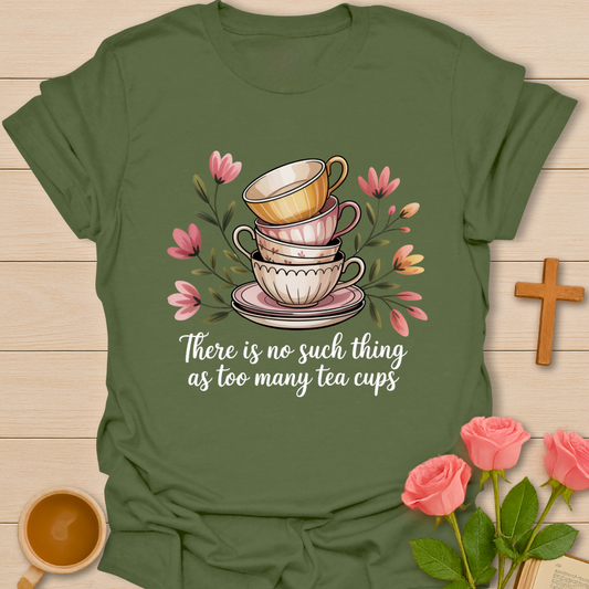 Green t-shirt with tea cup design and text on a wooden surface with flowers and a cross.