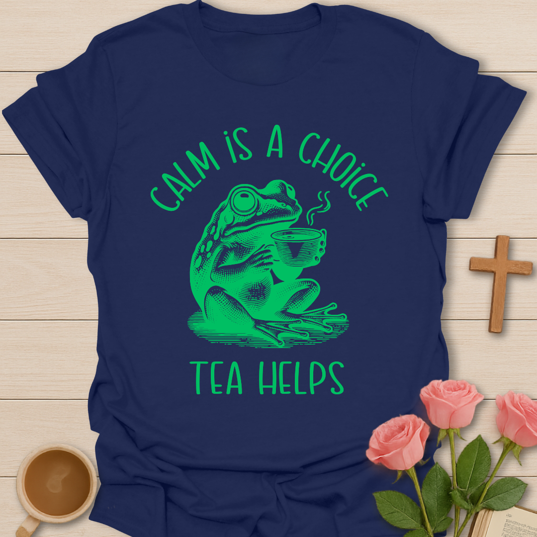 Navy blue t-shirt with green frog graphic and text on a wooden surface with coffee and roses.