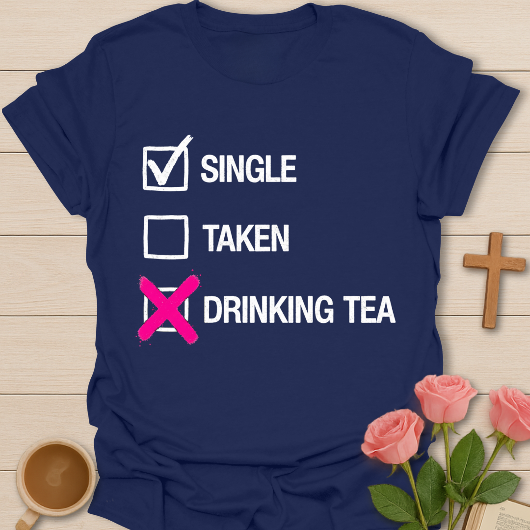 Navy blue t-shirt with humorous text design on a wooden surface with flowers and a cup.