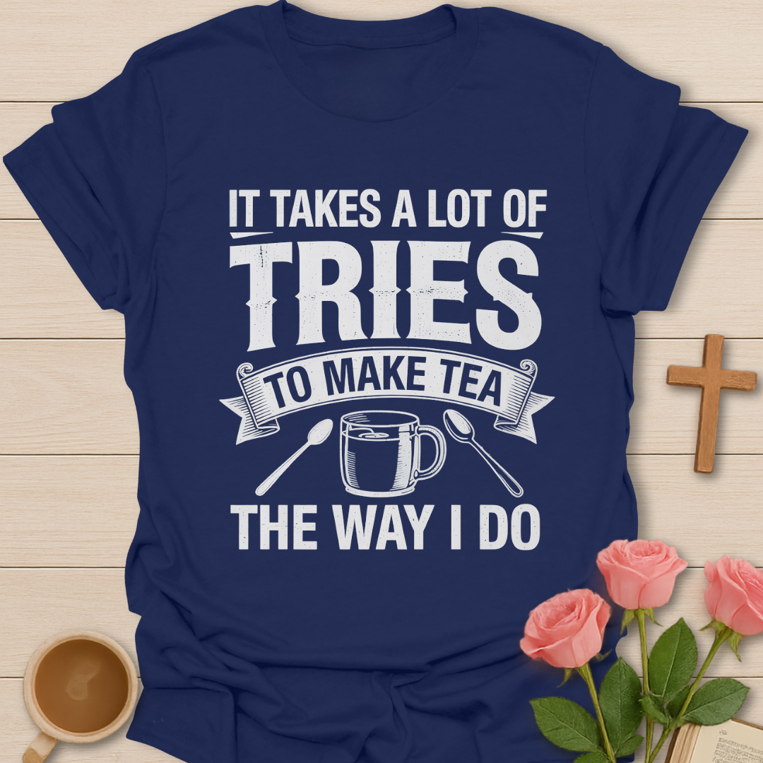 Navy blue t-shirt with humorous tea-making quote on a wooden surface with coffee and roses.