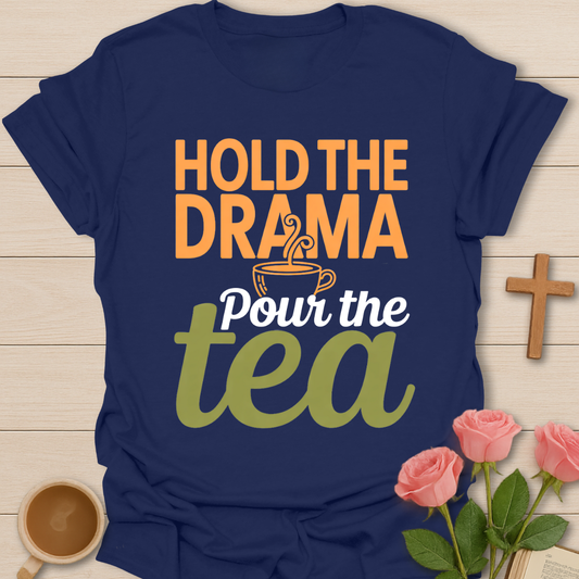 Navy blue t-shirt with typography design reading “Hold the Drama, Pour the Tea” with a steaming tea cup illustration in warm, cozy colors.