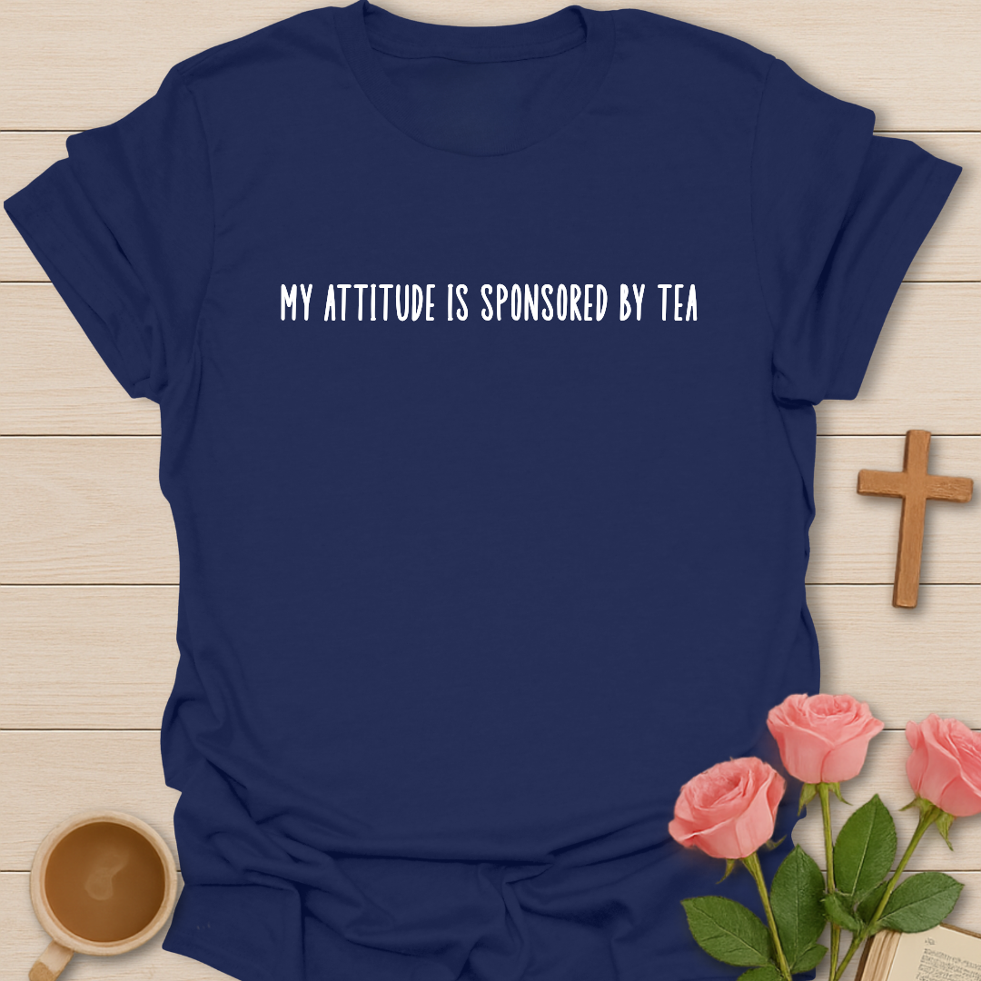 Navy blue t-shirt with 'My attitude is sponsored by tea' text on a wooden surface with a cup of coffee and roses.