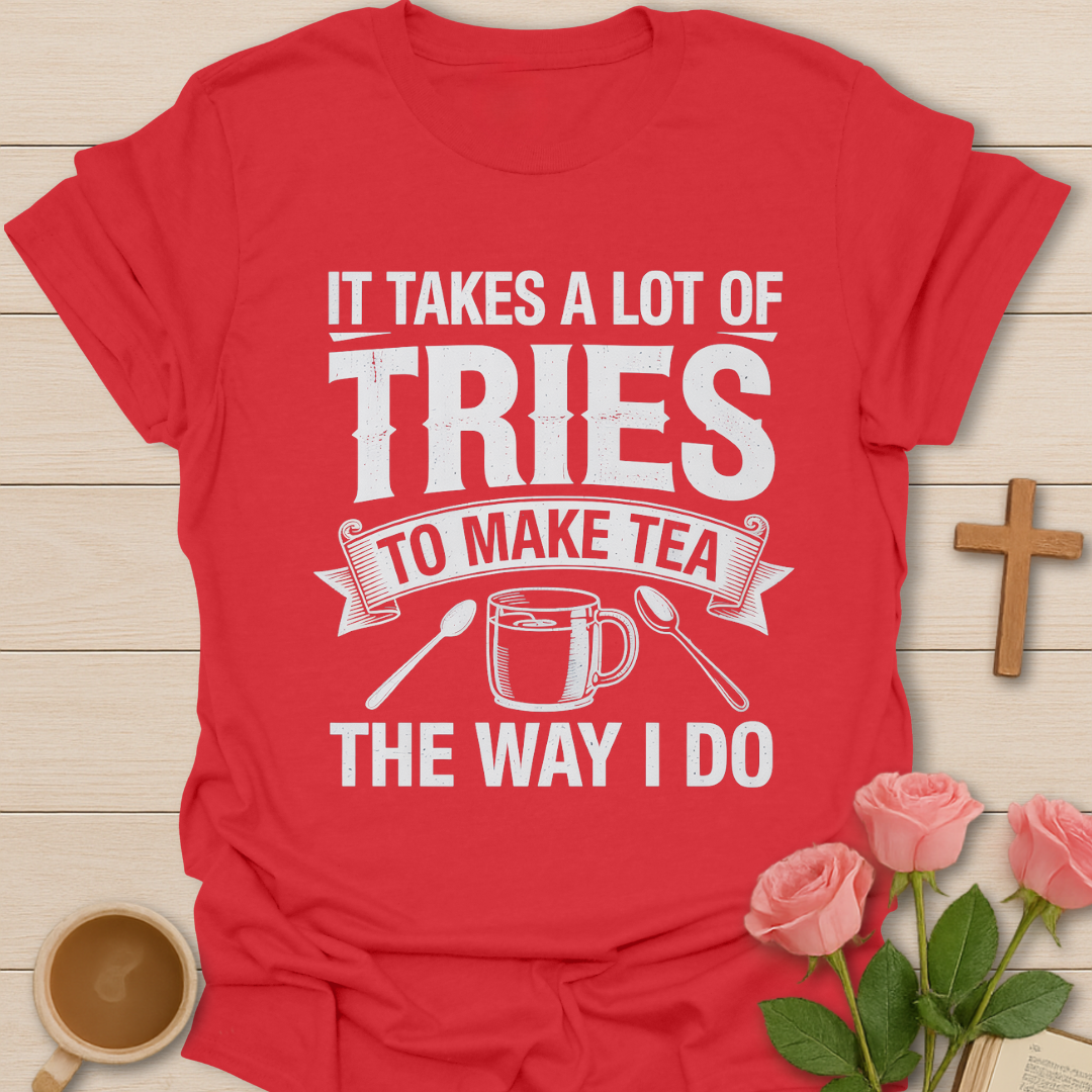 Red t-shirt with white text and graphics on a wooden surface with a cup of tea and roses.