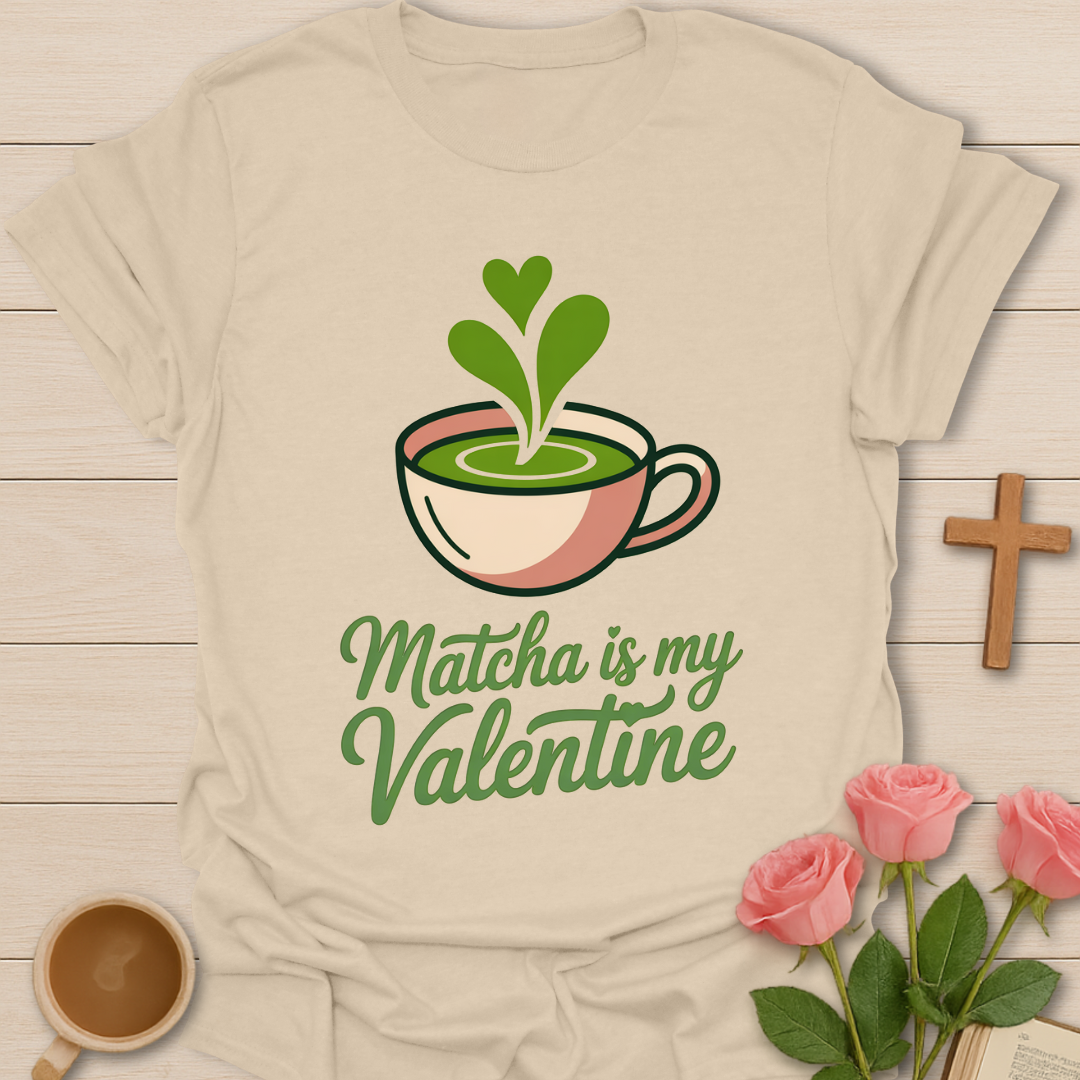 Beige t-shirt with matcha-themed design and text 'Matcha is my Valentine' on a wooden surface with flowers and a cup.