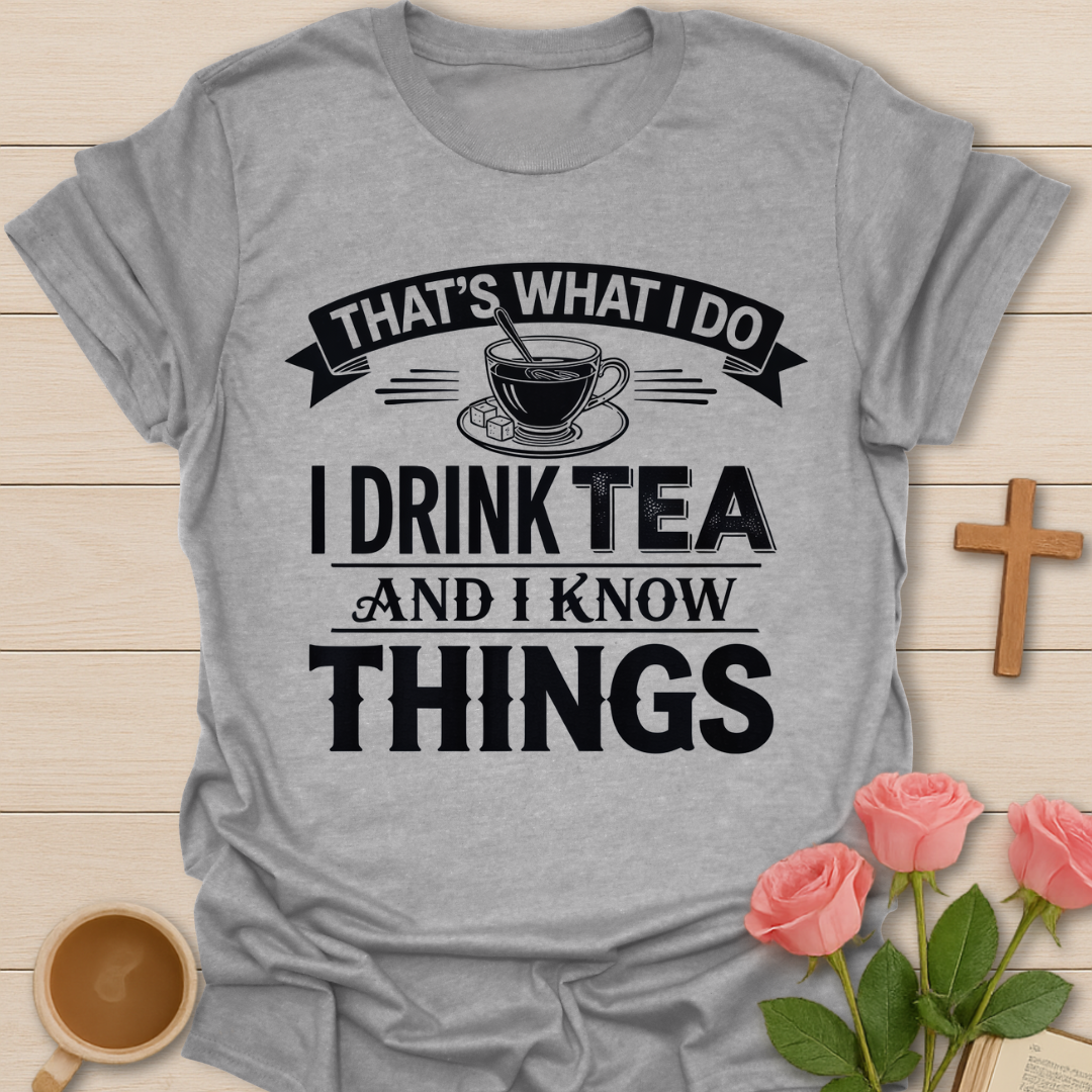 Gray t-shirt with tea-themed text design on a wooden surface with a cup of tea and roses.