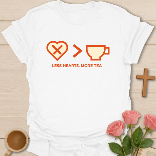 White t-shirt with a graphic design featuring hearts and a cup, text 'LESS HEARTS, MORE TEA', on a wooden surface with a cup and roses.