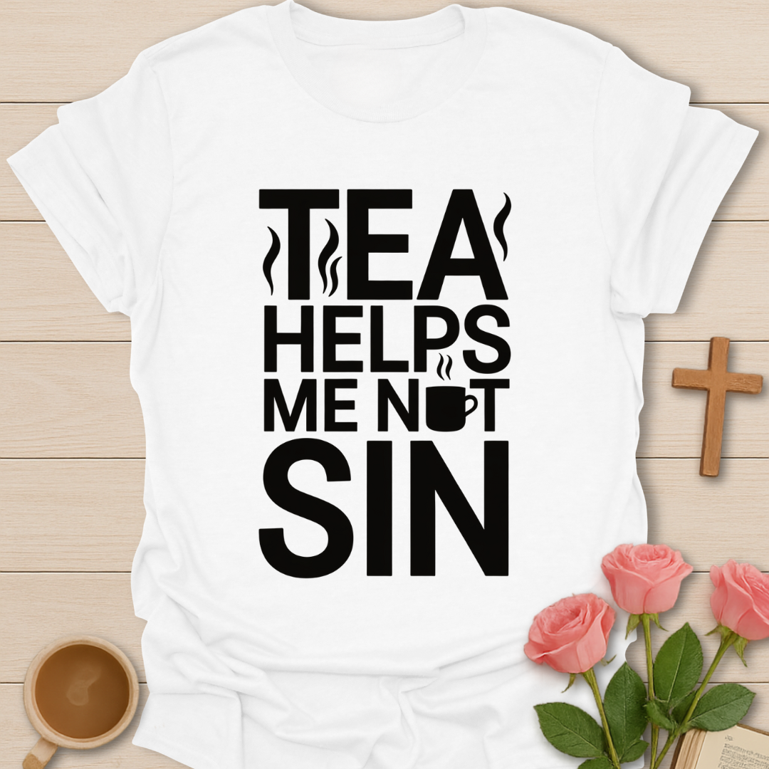 White t-shirt with 'Tea Helps Me Not Sin' text on a wooden surface with a cup, roses, and cross.
