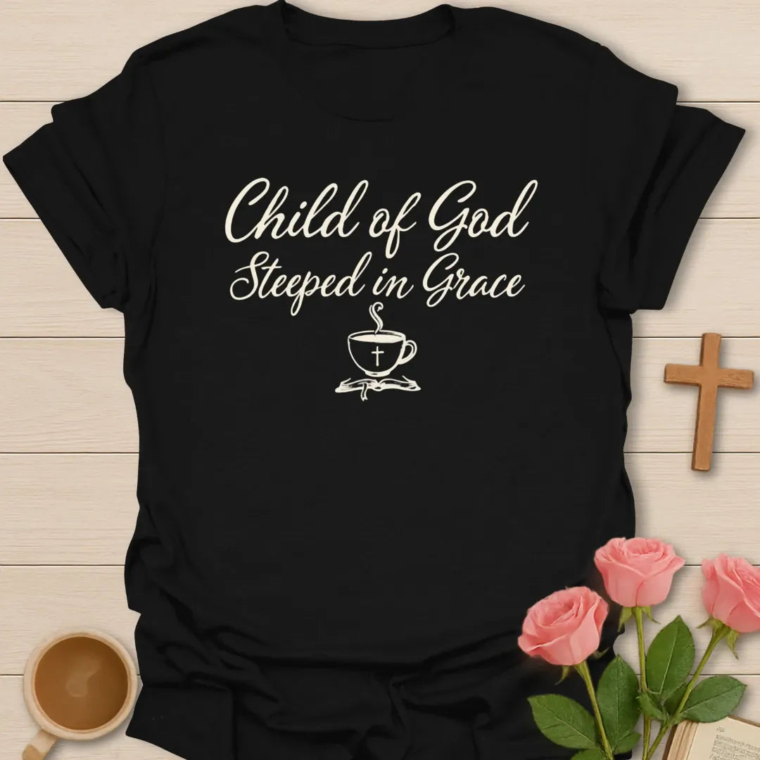 Child of God Steeped in Grace shirt with cream script lettering, teacup with cross, and minimalist faith design. - Black