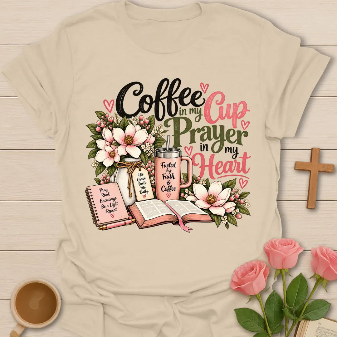 Coffee In My Cup, Prayer In My Heart Christian t-shirt with pink flowers, an open Bible, a prayer journal, and a coffee tumbler - Sand