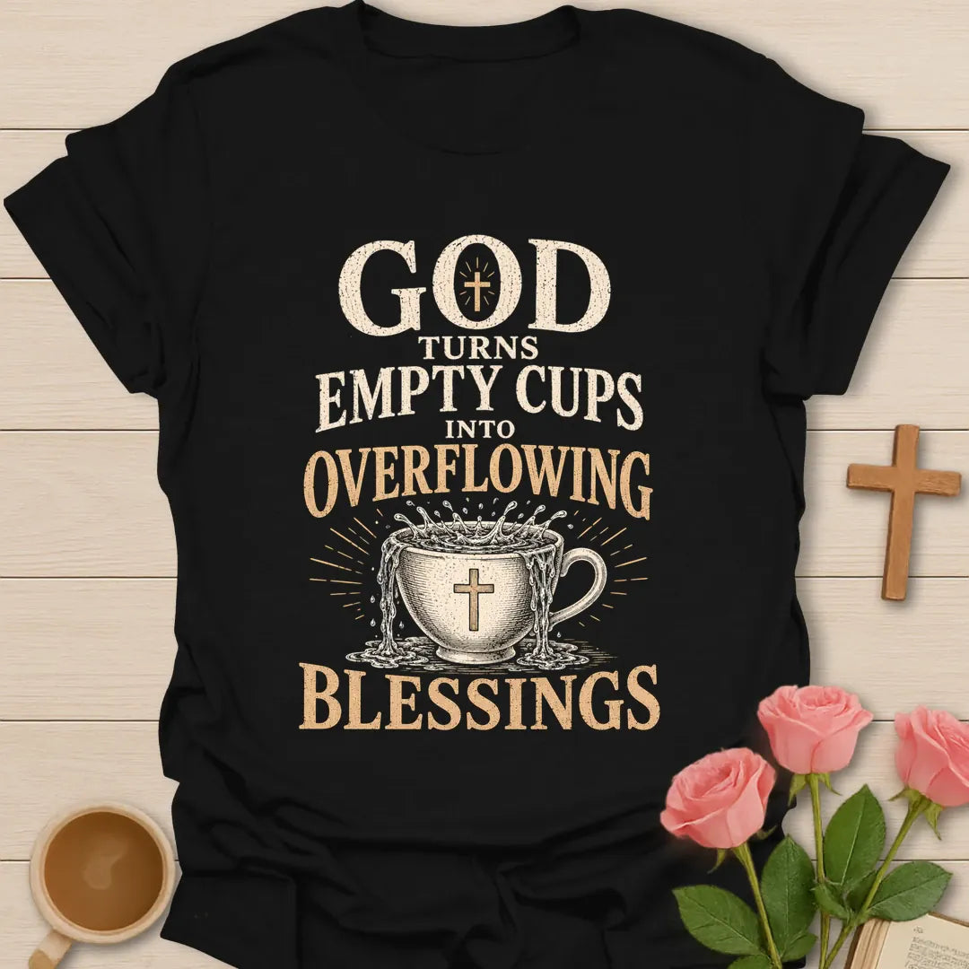 God Turns Empty Cups Into Overflowing Blessings t-shirt with vintage lettering and an overflowing teacup marked with a cross. - Black