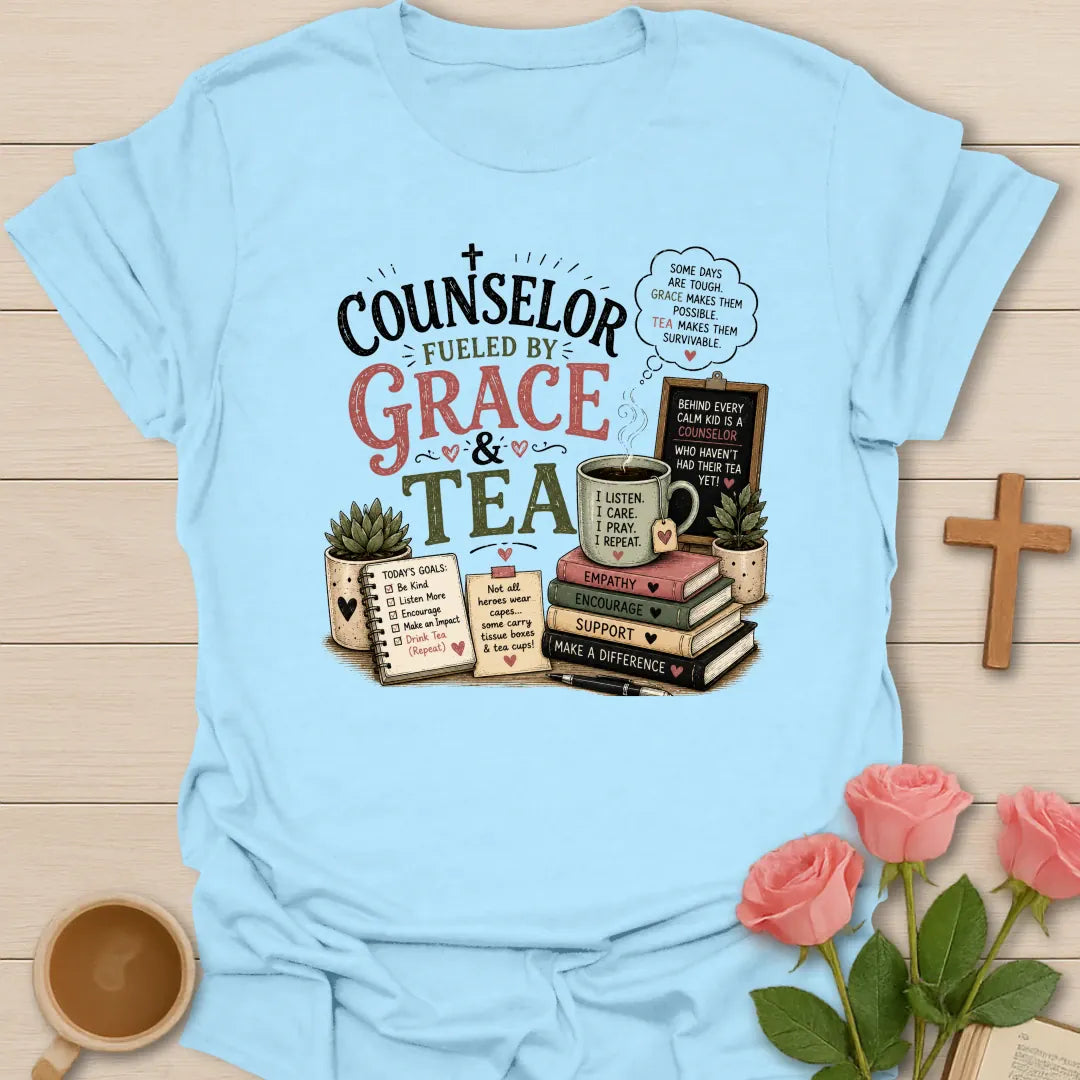 Counselor Fueled by Grace and Tea shirt with stacked books, teacup, chalkboard, notebook, plant, and vintage pink and sage lettering. - Light Blue