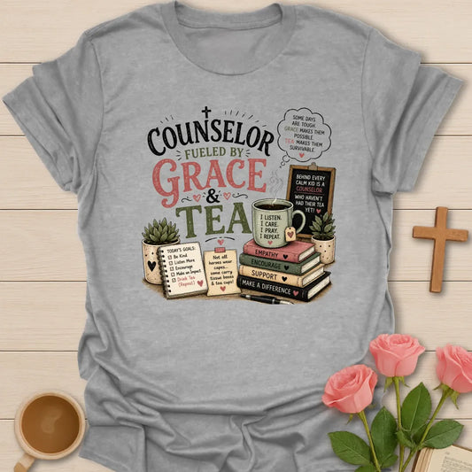 Counselor Fueled by Grace and Tea shirt with stacked books, teacup, chalkboard, notebook, plant, and vintage pink and sage lettering. - Sport Grey