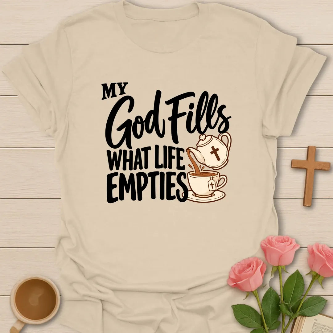 My God Fills What Life Empties Christian t-shirt with a teapot marked with a cross pouring into a teacup - Sand