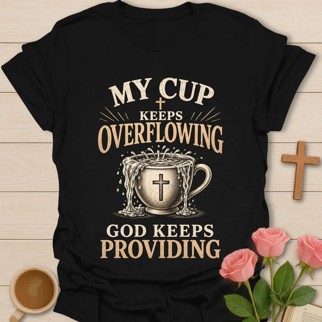 My Cup Keeps Overflowing, God Keeps Providing t-shirt with vintage lettering and an overflowing teacup marked with a cross. - Black