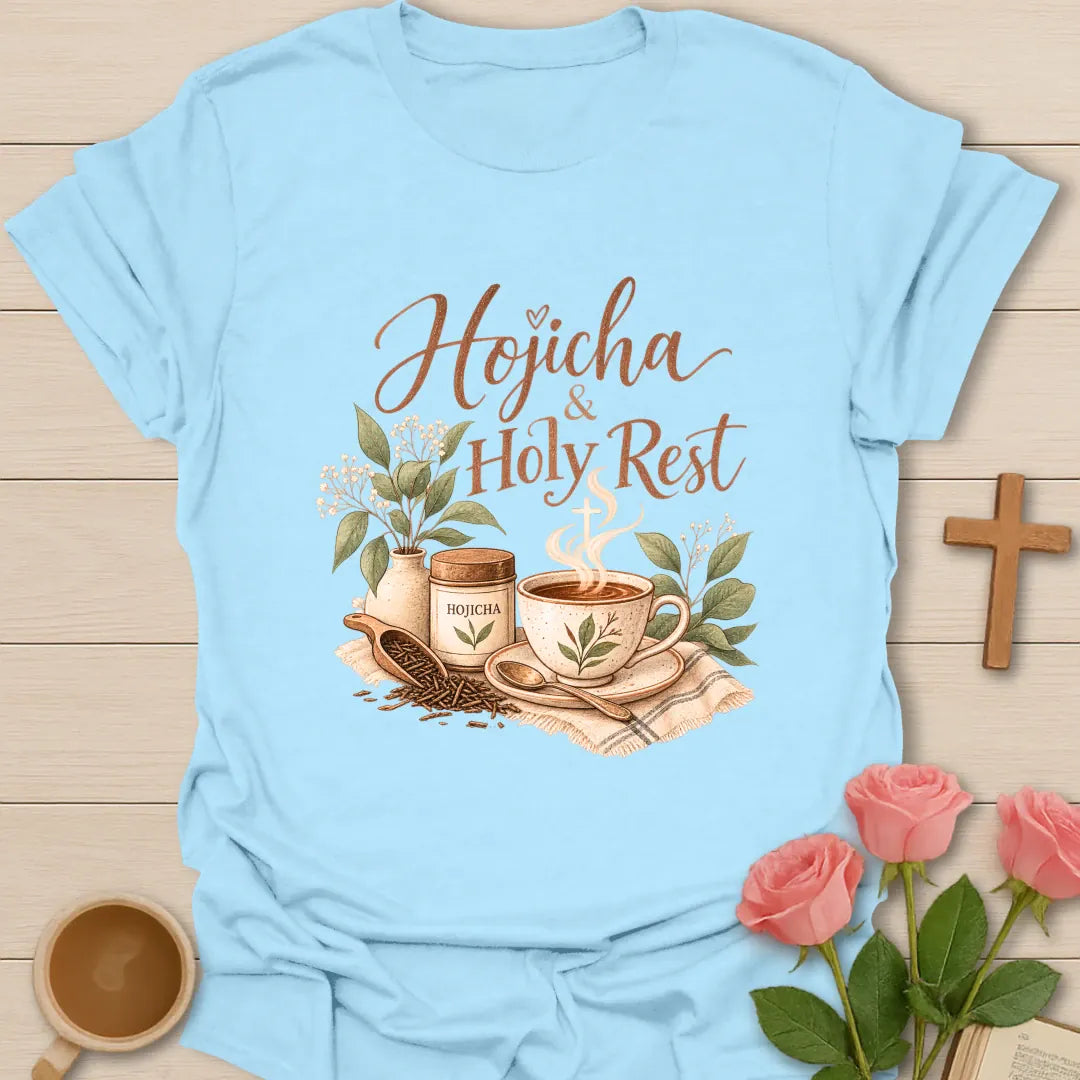 Hojicha & Holy Rest t-shirt with script lettering, a hojicha tea tin, a teacup with cross-shaped steam and a scoop of roasted tea leaves. - Light Blue