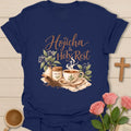 Hojicha & Holy Rest t-shirt with script lettering, a hojicha tea tin, a teacup with cross-shaped steam and a scoop of roasted tea leaves. - Navy
