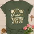 Holdin Peace and Trustin Jesus shirt with cream vintage lettering, script peace text, and bold stacked typography. - Military Green