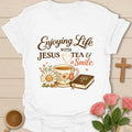 Enjoying Life With Jesus Tea and a Smile shirt with teacup, Bible, flowers, and heart-shaped steam. - White