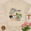 Joy Is Flowing Like A River shirt with teacup, Bible, river, mountains, sunrise, flowers, and tea faith text. - Sand