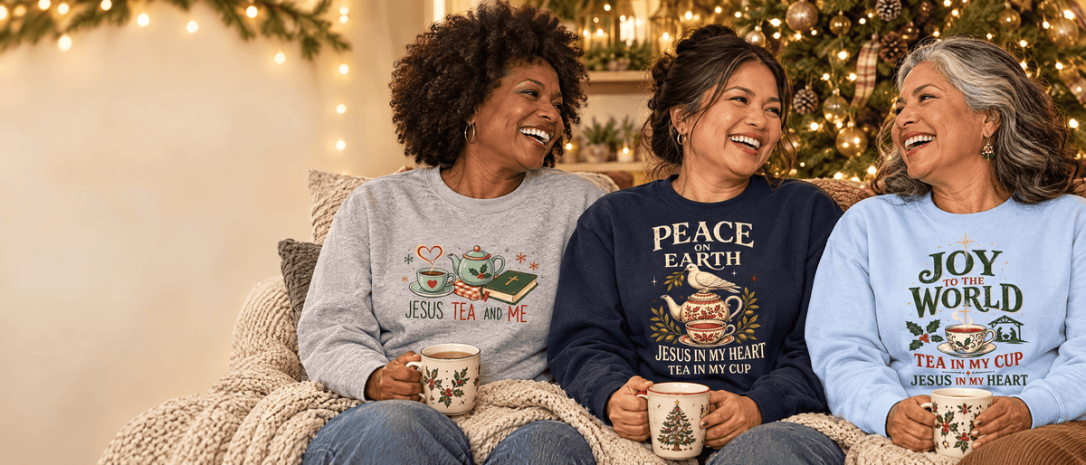 Three women friends by a Christmas tree in KozzyCo Jesus Tea & Me, Peace On Earth, and Joy To The World sweatshirts