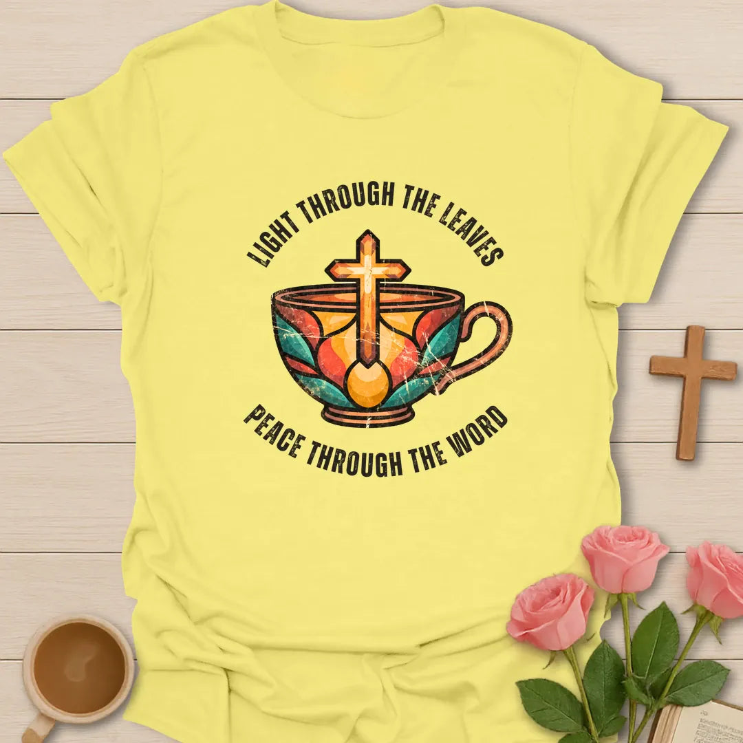 Light Through The Leaves, Peace Through The Word t-shirt with a stained-glass style teacup and golden cross - Cornsilk