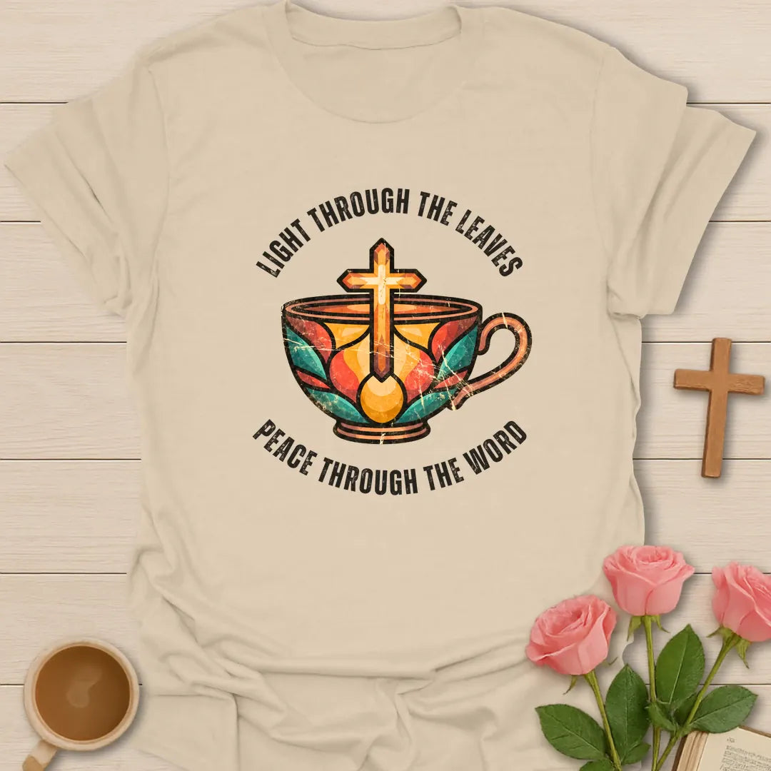 Light Through The Leaves, Peace Through The Word t-shirt with a stained-glass style teacup and golden cross - Sand