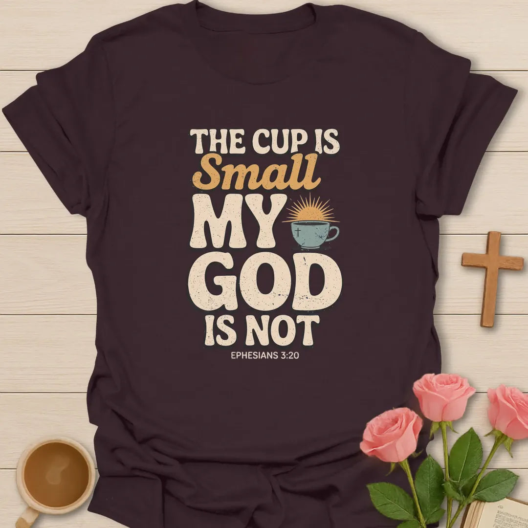 The Cup Is Small My God Is Not Christian t-shirt with bold lettering, a teacup with a cross and sunrise, and Ephesians 3:20 - Dark Chocolate