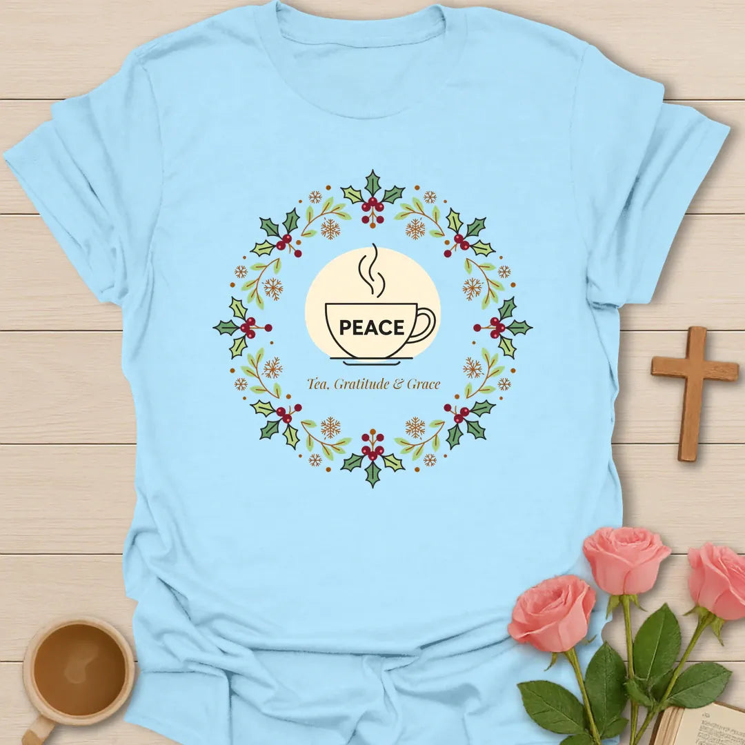 Peace Tea Gratitude and Grace shirt with teacup, wreath, holly berries, snowflakes, and peaceful Christmas design. - Light Blue