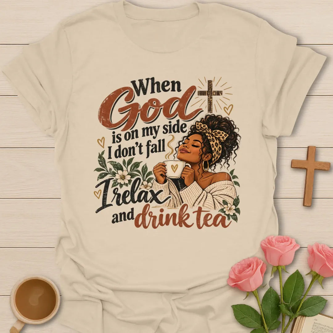 When God Is On My Side I Don't Fall, I Relax And Drink Tea Christian t-shirt with a woman in a leopard headband holding a teacup beside a glowing cross - Sand