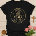 Sippin Chai Tea and Trustin Jesus shirt with mason jar chai, cross charm, circular badge, and cream vintage lettering. - Black