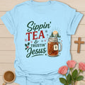 Sippin Tea and Trustin Jesus Christmas Christian T-shirt with tea mason jar cross and snowy trees - Light Blue