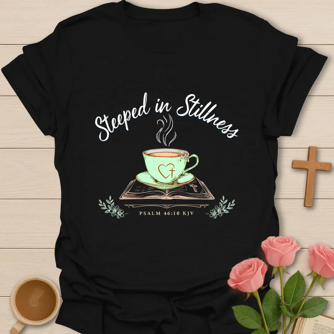 Steeped In Stillness Christian tea shirt with teacup, open Bible, floral accents, and Psalm 46:10 text. - Black