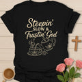 Steepin Slow and Trustin God shirt with teapot pouring tea, teacup, cross steam, floral line art, and cream lettering. - Black