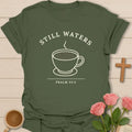 Still Waters shirt with simple teacup, steam, cream lettering, and Psalm 23:2 text. - Military Green