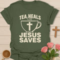 Tea Heals Jesus Saves shirt with bold cream lettering, teacup with cross, and distressed vintage texture. - Military Green